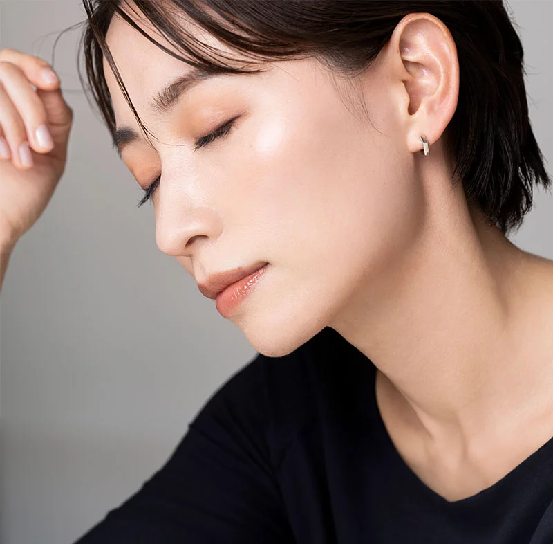 A close-up of an elegant Asian woman with smooth skin and short hair, wearing a black top, with her eyes closed and head slightly tilted downward, showcasing her calm and serene expression - Diamond Glow Facial in North Carolina