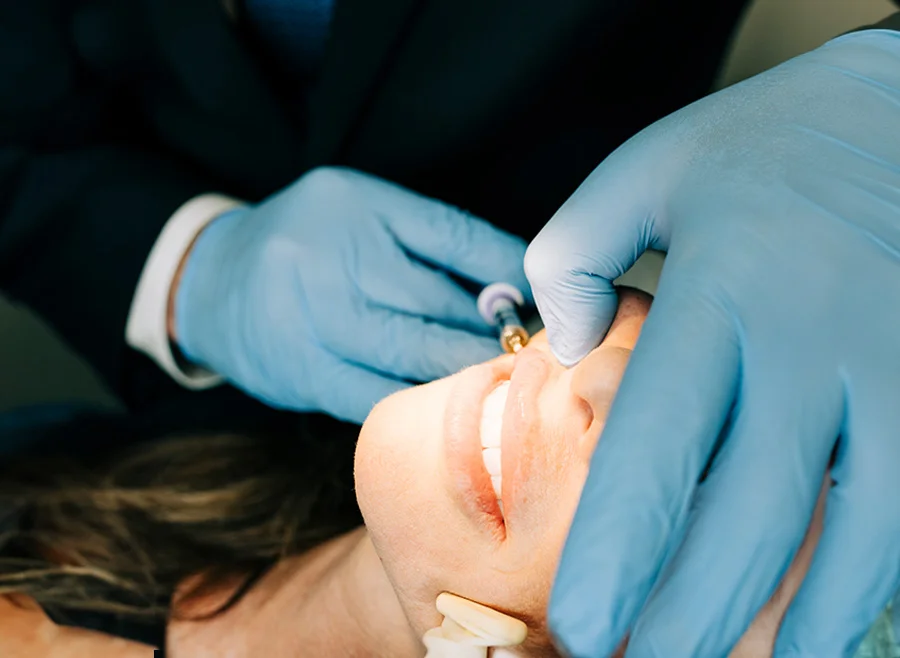 Close-up of a patient receiving a cosmetic procedure on their face, with a medical professional's gloved hands carefully performing the treatment - Lip Fillers in North Carolina