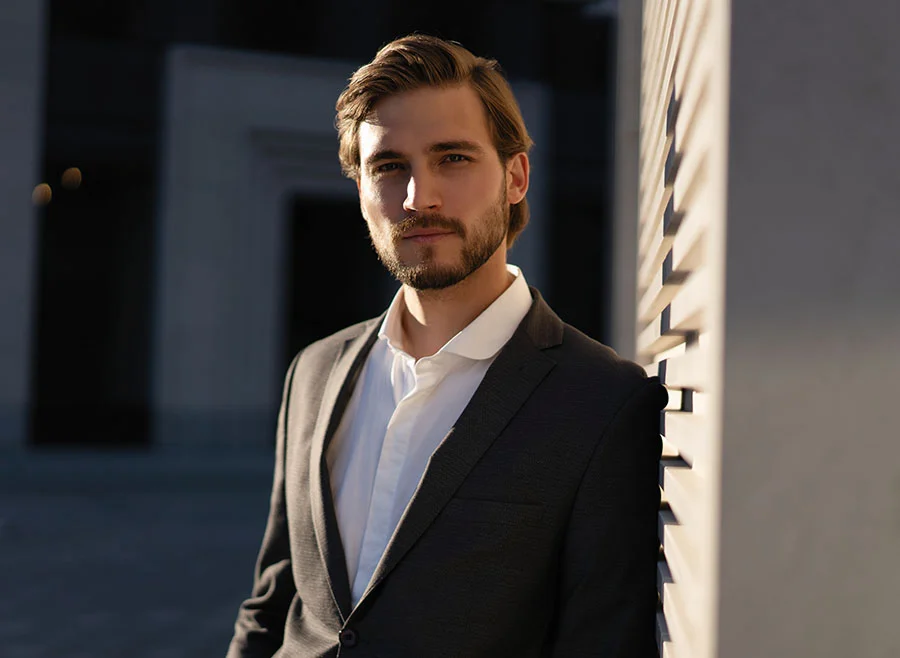 Man in a black blazer standing against a wall -Red Light Hair Treatment in North Carolina